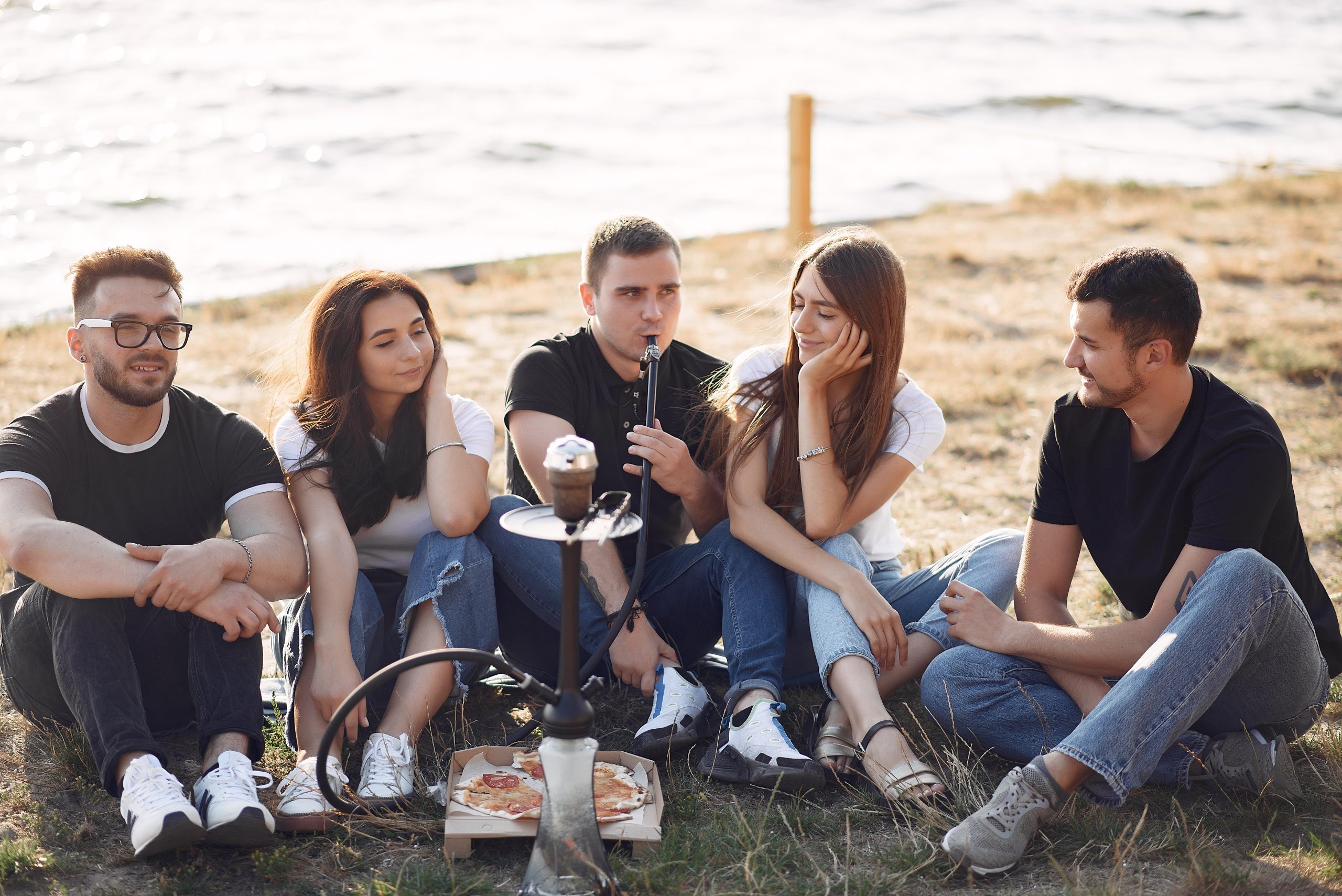 young-people-eating-pizza-smoking-shisha-beach